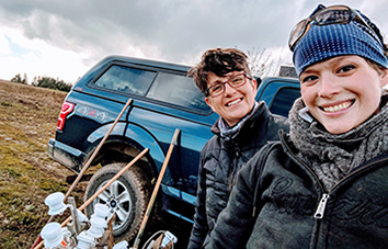 Two researchers posed in front of their truck in a farm field.